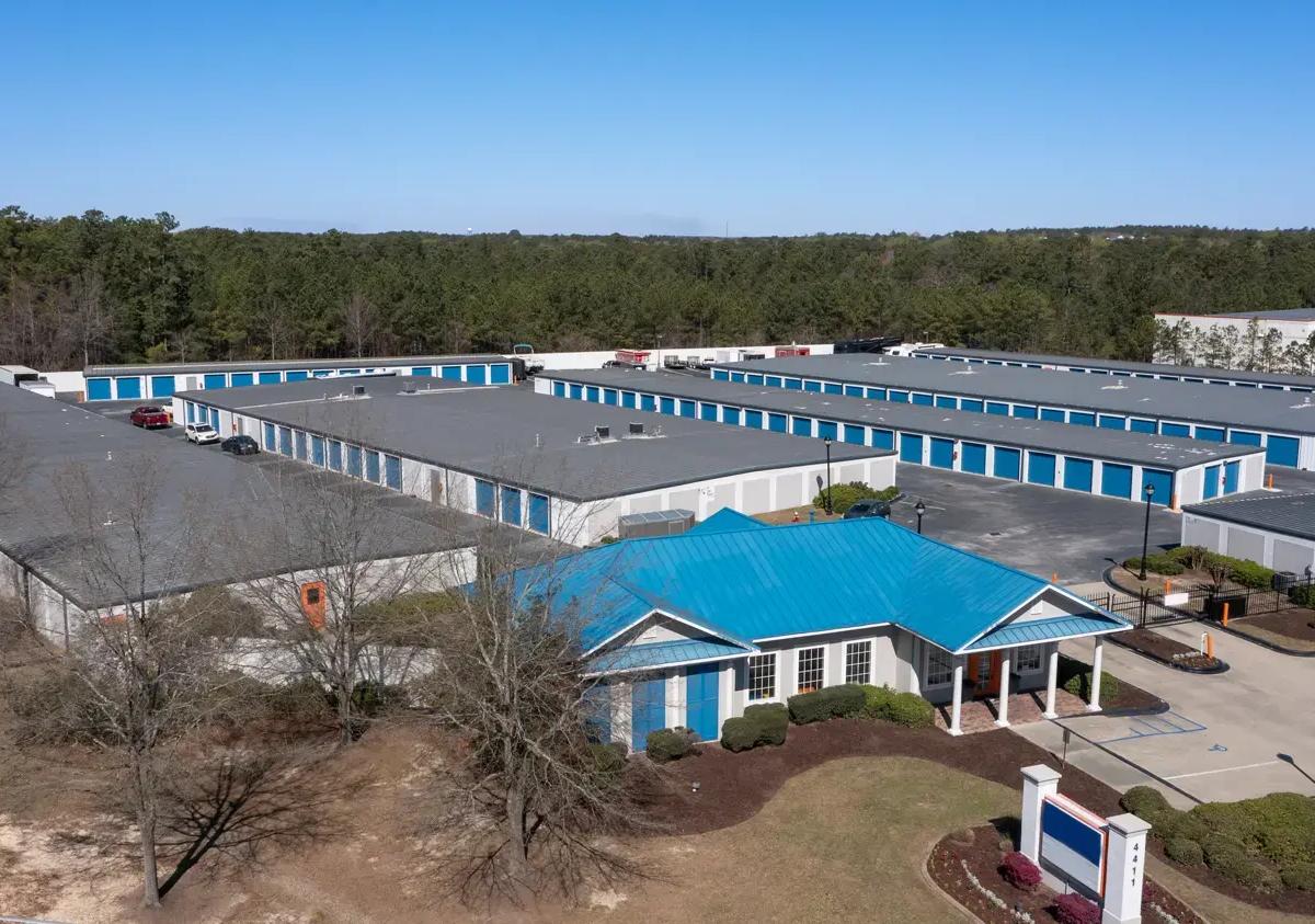 Aerial view of a storage facility featuring a blue-roofed office building and several long rows of units