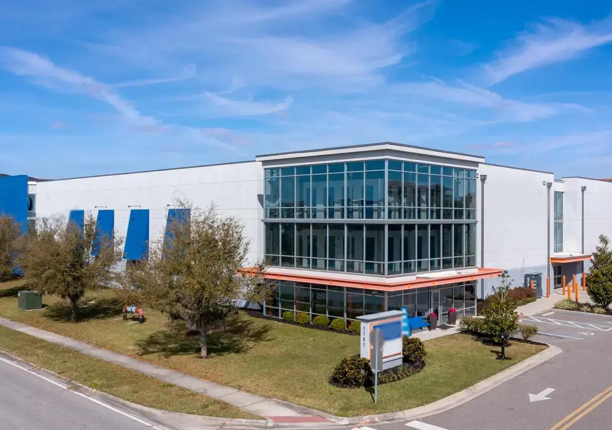 A modern multi-story self-storage building with large glass windows and an orange awning under a blue sky