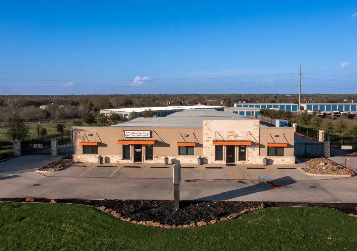 Main office building with orange awnings and a paved parking lot in front of storage units